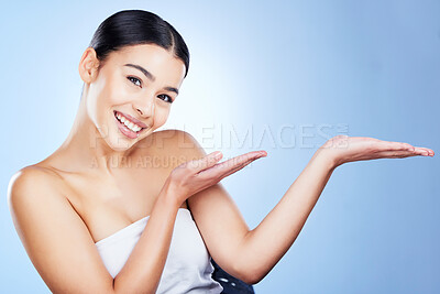 Buy stock photo Skincare, portrait and space gesture of woman with hands showing mockup for cosmetic promotion. Wellness marketing, smile and spa dermatology of a young model in isolated, blue background and studio