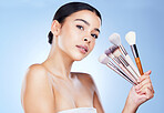 Makeup, beauty brushes and portrait of woman on blue background for cosmetics, powder and foundation. Cosmetology, salon aesthetic and face of girl with tools for application, wellness and skin glow