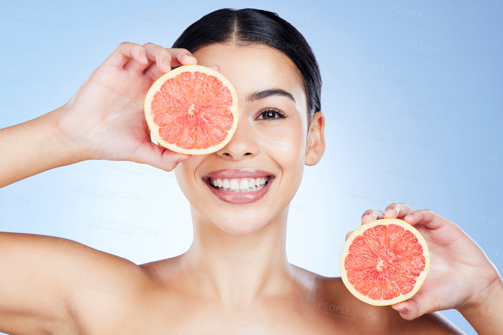 Buy stock photo Woman, hands and grapefruit for skincare nutrition, vitamin C or healthy diet against a blue studio background. Happy female smile holding organic fruit for citrus health, facial or beauty wellness