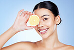 Lemon, citrus and woman with Vitamin C fruit for facial detox isolated against studio blue background. Cosmetics, skincare and portrait of self care model covering eye with food for smooth skin