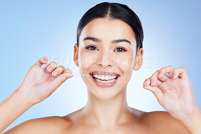 Buy stock photo Face, flossing teeth and hygiene with woman, dental and beauty with grooming and mouth care on blue background. Hands, string and healthy gums with fresh breath, health and skin glow in portrait