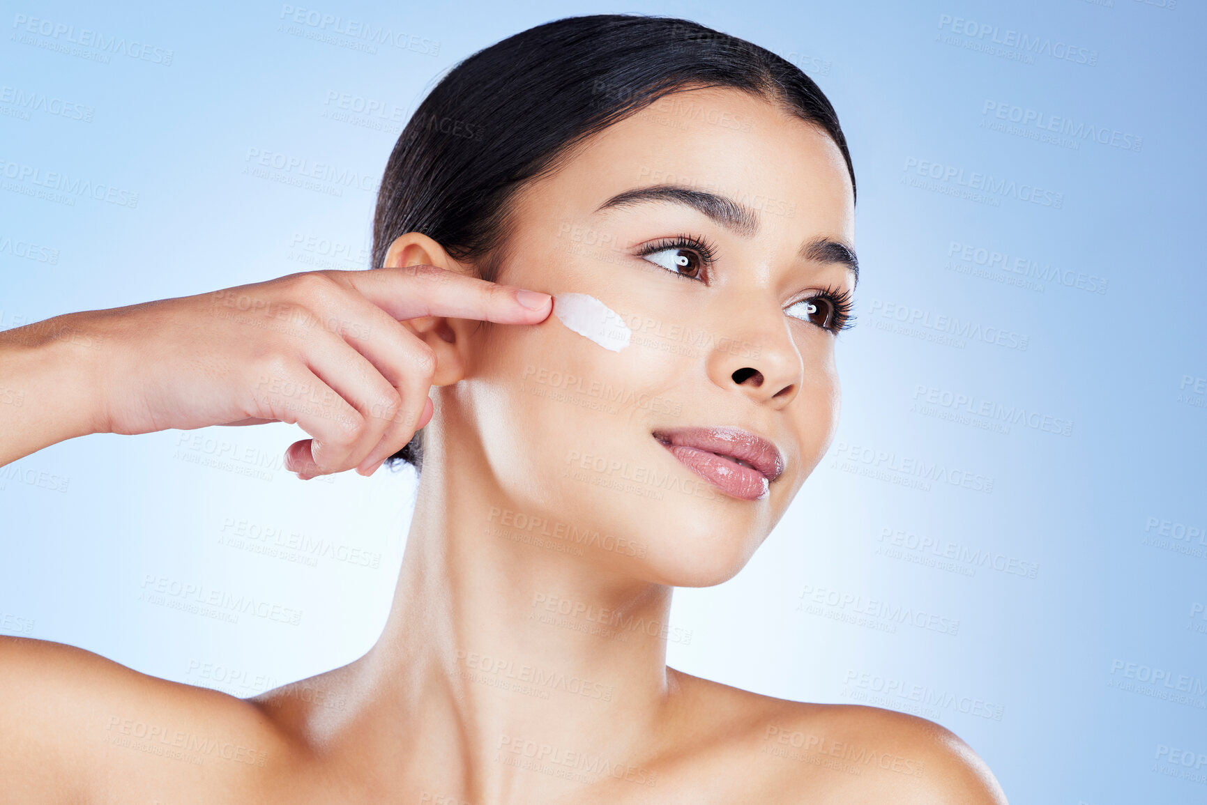 Buy stock photo Woman, face and hand for skincare moisturizer in cosmetics or beauty against a blue studio background. Female applying product, lotion or cream for facial treatment, collagen or healthy self care