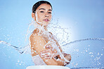 Beauty, skin care and portrait of woman water splash for glow results on blue background. Face of aesthetic model person with spa facial, cosmetics or makeup for health, wellness and dermatology