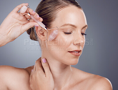 Buy stock photo Rose quartz, facial massage and woman with face roller for wellness, dermatology and skincare. Isolated, gray background and model with beauty for facelift and self care with crystal in studio