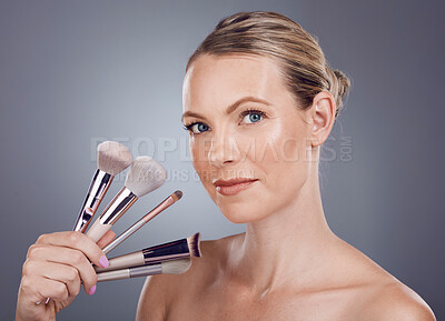 Buy stock photo Face, tools for makeup and woman in portrait, beauty and skin glow with facial and foundation on studio background. Powder, cosmetics brush and skincare with shine, cosmetology and cosmetic care