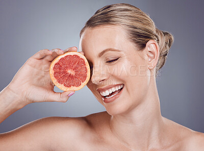 Buy stock photo Grapefruit, laughing face and woman with beauty on studio background, wellness benefits or smile. Happy model, citrus fruits and diet for natural detox, healthy skincare or vitamin c aesthetic