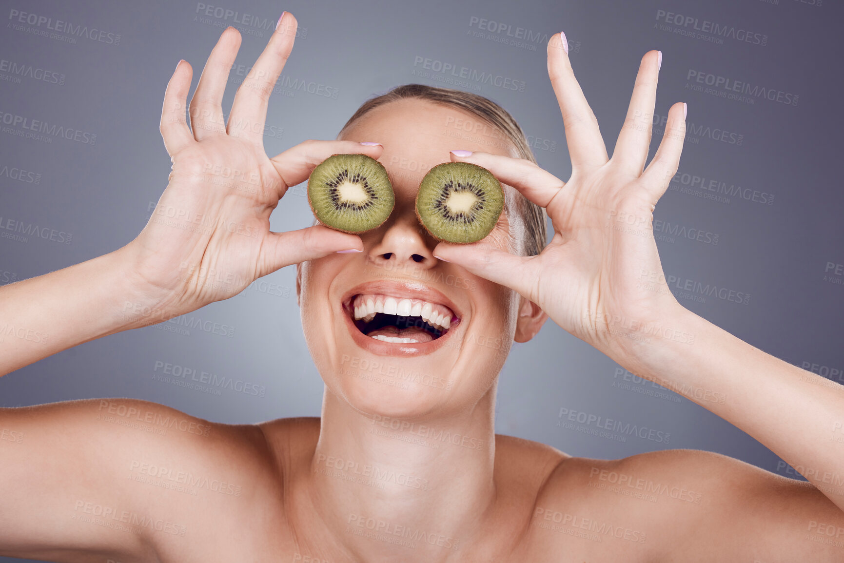 Buy stock photo Kiwi, woman and cover eyes for beauty, skincare and wellness food on studio background. Happy model, smile and organic green fruits for natural cosmetics, detox and nutrition benefits of funny face
