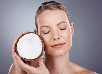 Buy stock photo Coconut, woman and skincare for wellness in studio, healthy food and aesthetic face benefits. Beauty model, tropical fruits for oil and natural cosmetics of facial nutrition, glow and spa background