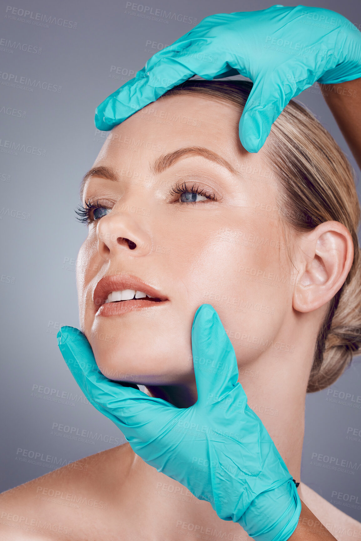 Buy stock photo Woman, studio and surgeon hands for cosmetic surgery, facial transformation and beauty by gray background. Model, anti aging and headshot with consulting, skincare and inspection for face aesthetic