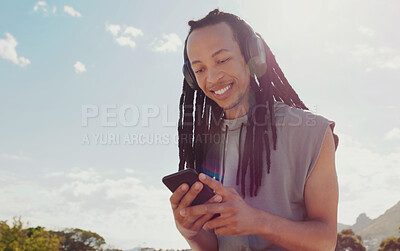 Buy stock photo Sky, black man and smartphone with headphones streaming music, online reading and podcast outdoor. African American male, guy and cellphone for social media, headset and listen to audio and sounds