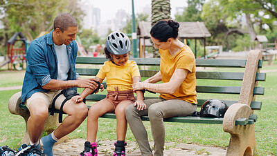 Buy stock photo Parents, park bench and helmet with kid, help and safety for skating, rollerskate or bike. Interracial family, mom and dad with helping hand, teaching and girl kid for bonding, learning and exercise