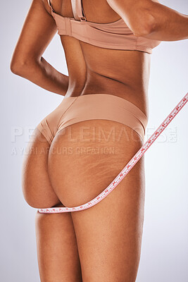 Buy stock photo Woman, ass and tape measure in body care, cellulite or weight loss against a gray studio background. Female buttocks measuring size in underwear or lingerie for fitness, diet or healthcare wellness