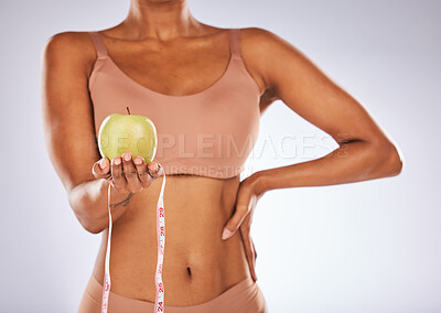Buy stock photo Woman, hands and apple with measuring tape for healthy diet or weight loss against a gray studio background. Female in underwear holding fruit for slim dieting health, body care or wellness nutrition