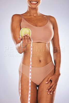 Buy stock photo Woman, hands and apple with tape measure for healthy diet or weight loss against a gray studio background. Female in underwear holding fruit for slim dieting health, body care or wellness nutrition