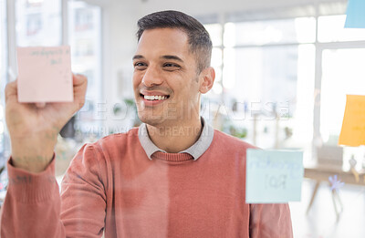 Buy stock photo Creative man, writing and planning schedule, strategy or brainstorming on glass wall at office. Happy employee worker in project plan, tasks and write for post it or sticky note smiling for startup