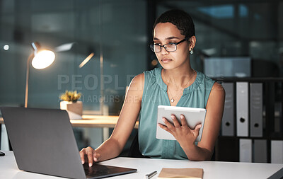 Buy stock photo Serious, accountant or black woman at night on laptop and tablet for financial strategy, tax or audit review for company growth. Finance or advisor for planning stock market, investment research
