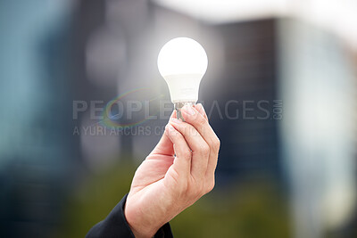 Buy stock photo Hands, light bulb and idea in the city for solution, eco friendly or renewable energy on blurred background. Hand of person holding lamp for creativity, ideas or power saving element on mockup