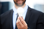 Businessman, hands and light bulb with idea in the city for solution, eco friendly or renewable energy. Hand of male employee holding lamp for creativity, ideas or power saving element on mockup