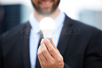 Buy stock photo Businessman, hands and light bulb with idea in the city for solution, eco friendly or renewable energy. Hand of male employee holding lamp for creativity, ideas or power saving element on mockup