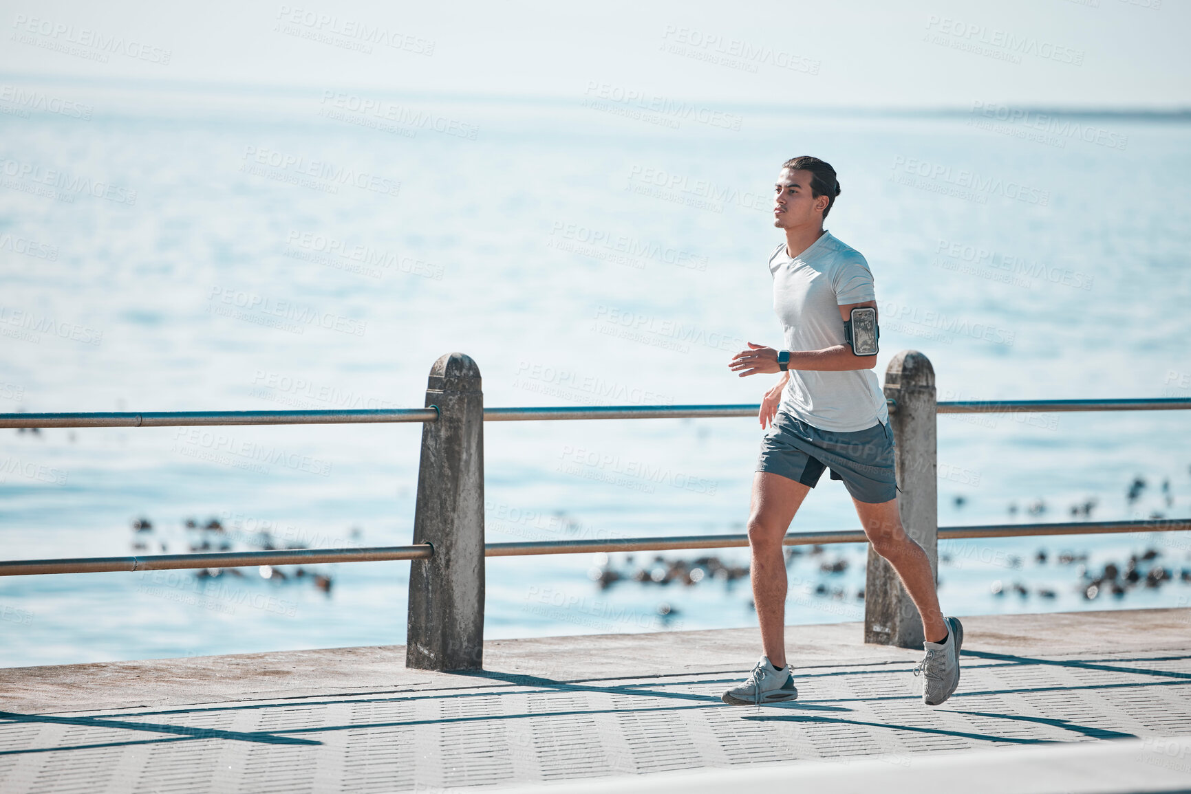 Buy stock photo Sports, fitness and man running by ocean in action for wellness, performance and athlete endurance. Nature, motivation and male runner by sea for exercise mockup, marathon training and cardio workout