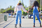 Rollerblading, holding hands and girl friends back on outdoor promenade with balance and skating. Woman, skate and friendship of women on summer holiday break doing a rollerskate activity on pavement