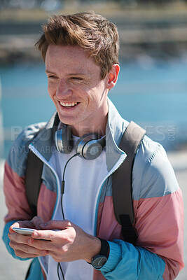 Buy stock photo Laughing, student and man with phone and headphones outdoor with mobile connection. Young person, happiness and blurred background of a male holding a cellphone for social media and text networking