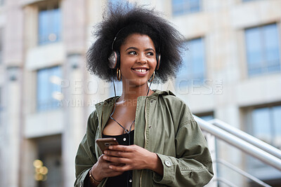 Buy stock photo Music, phone and gen z black woman with headphones in city to relax and smile outside in street. Urban fashion, enjoying online streaming radio service and trendy girl listening to audio on earphones