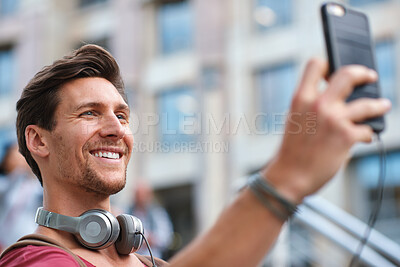 Buy stock photo Selfie, man and smile in the city for travel profile picture, social media and influencer streaming. Happiness, vacation and young person online with headphones and memories outdoor on holiday