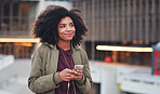 African american woman using smartphone in city wearing earphones listening to music with mobile phone