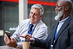 Mature businessmen using smartphone in city caucasian businessman talking to african american colleague showing mobile phone to friend