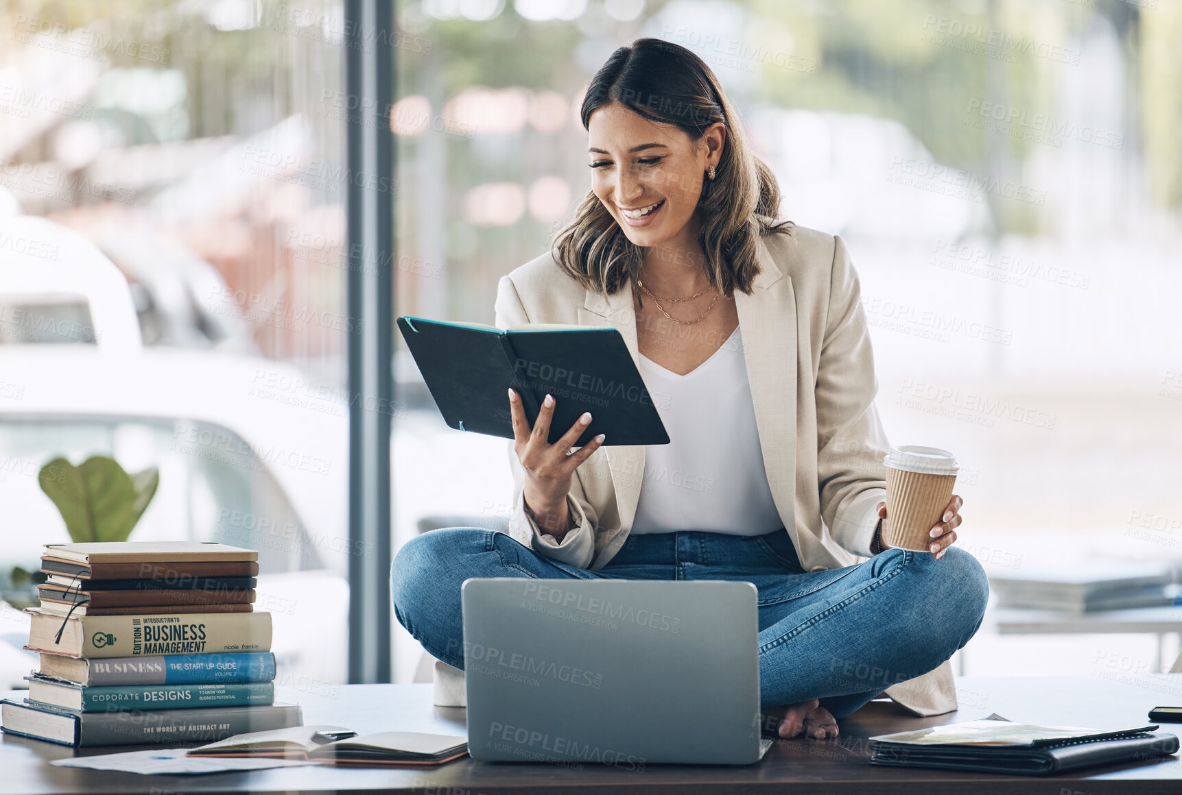 Buy stock photo Business woman, laptop or reading notebook while sitting on desk in marketing office, advertising company or creative startup. Smile, happy or relax worker with books, technology or innovation vision