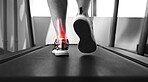 Closeup, treadmill and ankle with pain, injury and muscle tension with person walking, exercise and training. Zoom, athlete or foot with red highlight, gym equipment or strain after practice and ache