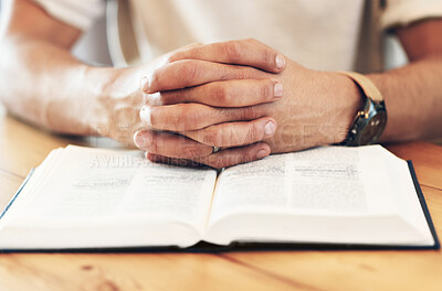 Religion, reading and hands of a man with a bible for prayer, worship and hope. God, christian and spiritual person with belief in Jesus, looking for support and help from a religious book on a table
