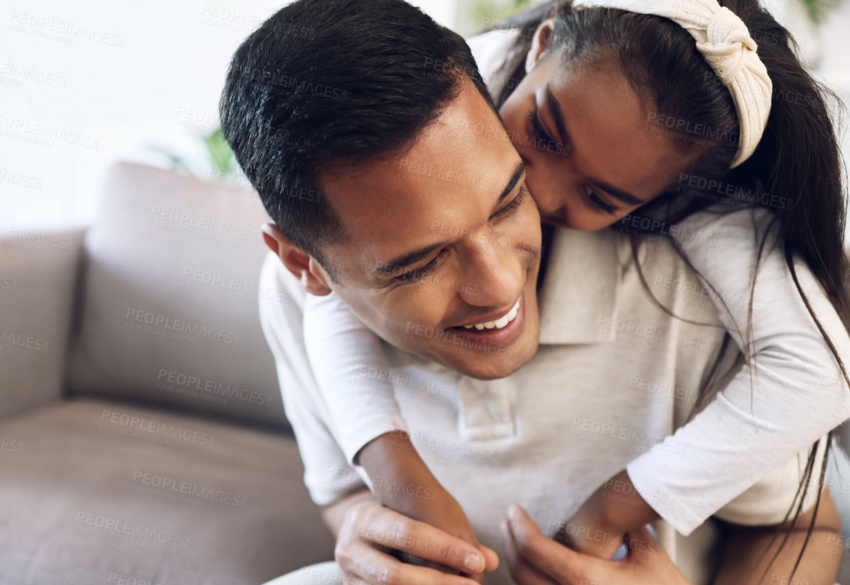 Buy stock photo Family, hug and girl with father on sofa, happy and laugh, kiss and bonding in their home. Embrace, smile and parent with child on couch, play or enjoy day off, weekend or piggyback in a living room