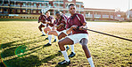Man, team and sports training with rope for fitness exercise, strength or workout on the grass field. Sport men or rugby players pulling ropes in tug of war, activity or practice for game or match