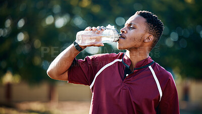 Buy stock photo Rugby, sports or black man drinking water in training, exercise or workout match on a field. Fitness, thirsty or tired African athlete drinks liquid in a bottle for energy or hydration in summer