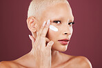 Portrait, face cream and beauty skincare of woman in studio isolated on red background. Dermatology aesthetic, cosmetics and young female model with lotion, creme or moisturizer for facial treatment.