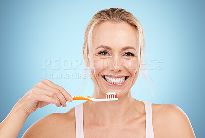 Buy stock photo Woman, toothbrush and smile with teeth for dental care, dentist or oral hygiene against a blue studio background. Portrait of happy mature female smiling in satisfaction for mouth or gum treatment