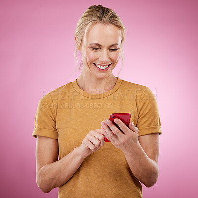 Buy stock photo Woman, phone and typing online for communication, social media and chat on pink background. Happy mature model with smartphone in hands for network connection or writing post on mobile app website