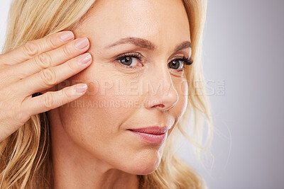 Buy stock photo Face, skincare and antiaging with a mature woman in studio on a gray background for natural beauty. Hand, wellness and facial with a senior female touching her skin for luxury cosmetic treatment