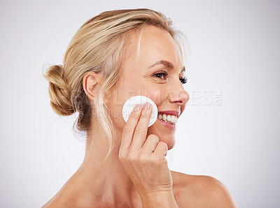 Buy stock photo Face, cotton and skincare with a mature woman in studio on a gray background cleaning her skin for exfoliation. Relax, luxury and product with a female using a pad to cleanse her pores for beauty 