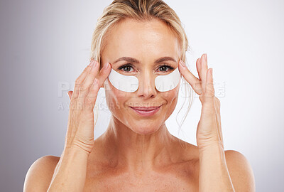 Buy stock photo Portrait, skincare and eye mask with a woman in studio on a gray background for beauty or antiaging treatment. Face, lift and collagen with an attractive female in the bathroom to apply a product