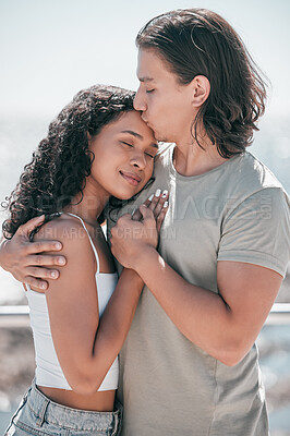 Buy stock photo Love, kiss and couple hug at beach, happy and outdoor for travel, romance and bond on blurred background. Forehead, kisses and man embracing woman, sweet and romantic, relation and traveling together