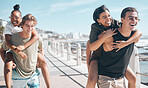 Diversity men, laughing and piggyback by beach, ocean or sea in social gathering, group vacation comedy or summer holiday. Smile, happy and couple of friends carrying women in travel, bonding or game