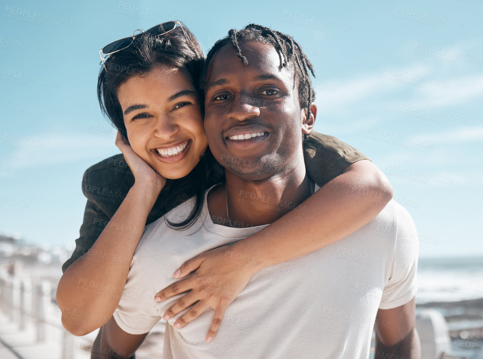 Buy stock photo Happy couple, portrait and piggyback by beach in relax romance holiday, love vacation date or summer travel location. Smile, bonding and man carrying black woman in fun game, freedom trust or support