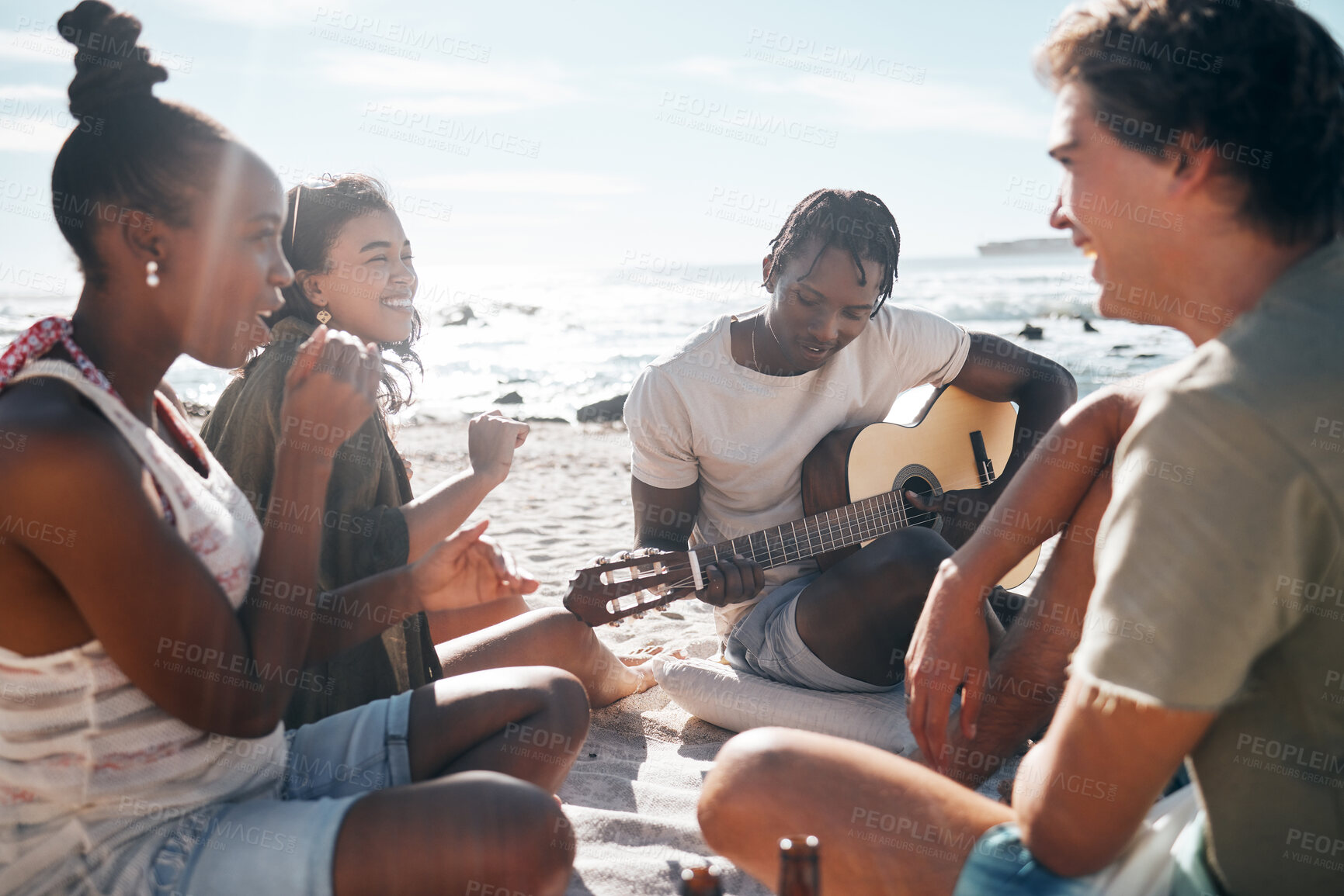 Buy stock photo Couple of friends, playing and guitar by beach, ocean or sea in holiday vacation, summer travel or social gathering. Smile, happy and bonding diversity people with musical instrument in relax picnic