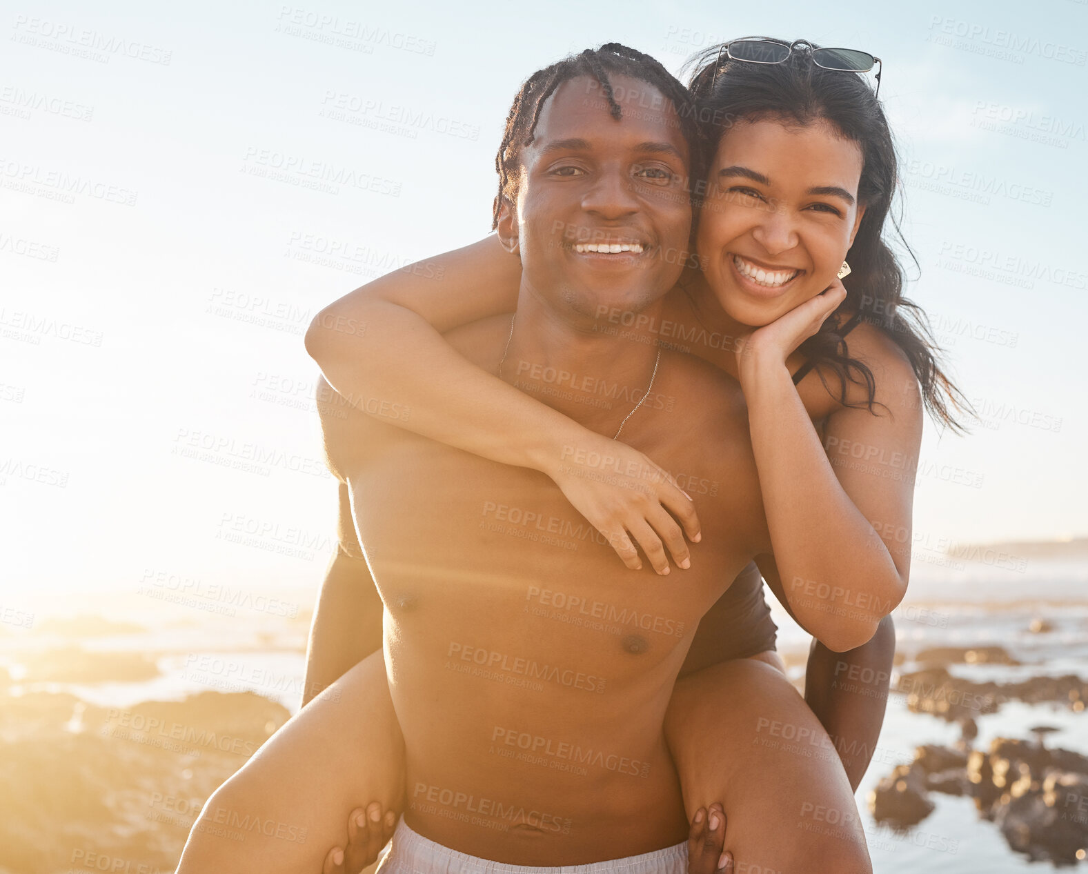 Buy stock photo Fun couple, portrait or piggyback on sunset beach, ocean or sea in energy holiday, love vacation or summer travel. Smile, happy or man carrying black woman in bonding games, freedom trust or support