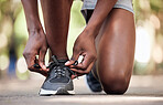 Hands, fitness and tie shoes at park to start running, training or workout outdoors. Sports, wellness and black man or male athlete tying sneakers to get ready for exercise, jog or cardio for health.