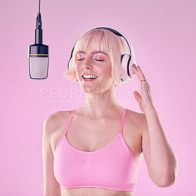Buy stock photo Headphones, microphone and woman singer in a studio recording a song, album or music. Happy, passion and young female artist or musician singing with equipment while isolated by a pink background.