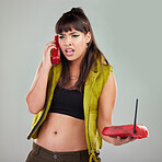 Angry, problem and woman with a telephone for a conversation isolated on a grey studio background. Stress, frustrated and mad girl speaking on a vintage landline phone for communication and conflict